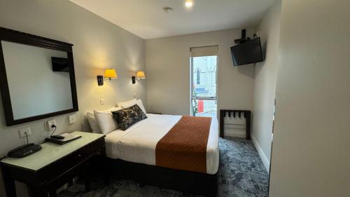 a bedroom with a bed and a desk and a mirror at Trinity Hotel in Wellington
