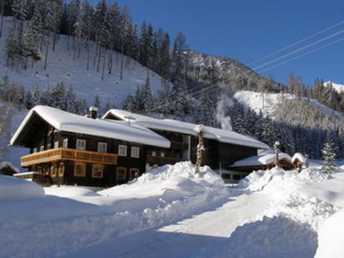 a snow covered building with a snow covered mountain at Birkenhof in Sankt Veit in Defereggen
