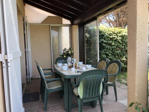 une table et des chaises vertes sur la terrasse dans l'établissement **Gruissan : Villa Climatisée, 6 Pers, Piscine, Accès Direct Plage, Parking, Commerces Proches** - FR-1-796-53, à Gruissan