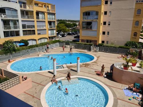 une vue aérienne de deux piscines dans un complexe d'appartements dans l'établissement Appartement T2 moderne avec piscines, garage et proche plage - Gruissan - FR-1-796-43, à Gruissan