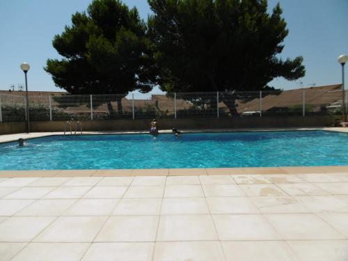 une piscine d'eau bleue et d'arbres dans l'établissement Appartement T2 Climatisé à Gruissan - Piscine, Plage, Parking & Terrasse - Idéal Familles 4/5 pers. - FR-1-796-45, à Gruissan