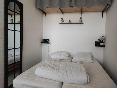 - un lit blanc dans une chambre avec un miroir dans l'établissement Studio spacieux à Gruissan - Parking - Vue port - Proche plage - FR-1-796-29, à Gruissan