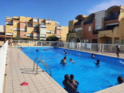 un groupe de personnes nageant dans une piscine dans l'établissement Studio centre port Gruissan, piscine, tennis, 2/3 pers - FR-1-796-31, à Gruissan