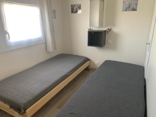 une petite chambre avec deux lits et une télévision dans l'établissement Gruissan, T3 climatisé sur plage, terrasse, 4 pers - FR-1-796-68, à Gruissan