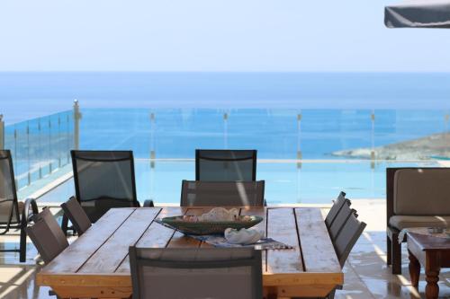 a wooden table and chairs with a view of the ocean at Ionian pool house in (( Lerë ))