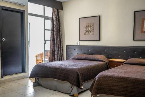 a bedroom with two beds and a window at Hotel María de la Luz in Valladolid