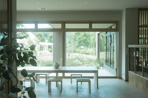 a table and chairs in a room with a large window at HOTEL & KOTEI SOKA in Kyotango