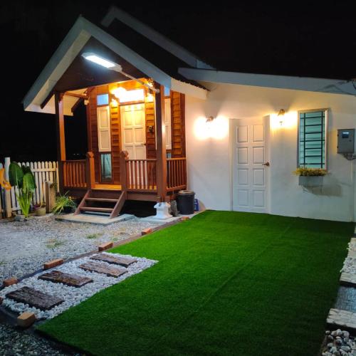 a house with a green lawn in front of it at Kampung Cottage Bagan Datuk in Selekoh