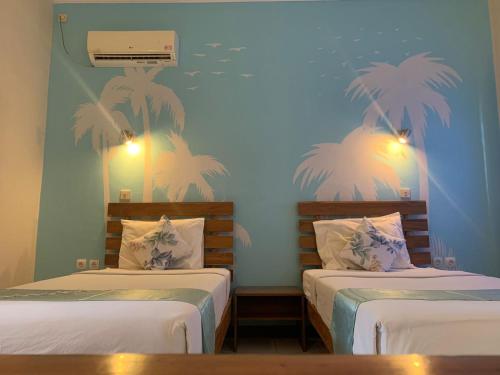 two beds in a room with palm trees on the wall at Medana Bay Marina in Paloh