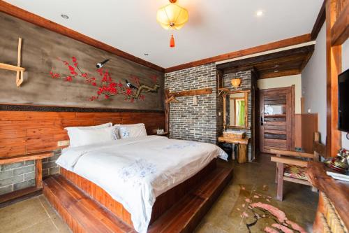 a bedroom with a bed and a brick wall at Butterfly Flowers Inn in Zhangjiajie