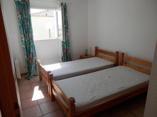 deux lits dans une petite pièce avec une fenêtre dans l'établissement Villa Climatisée à Gruissan, Proche Plage Grazel, 6 Pers, Parking Privé, Terrasse, Équipée - FR-1-796-70, à Gruissan
