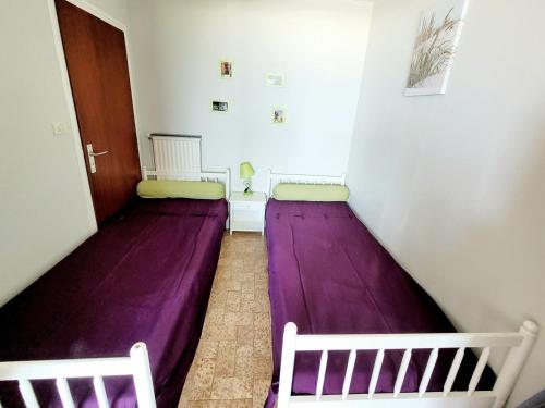 - 2 lits dans une chambre avec des draps violets dans l'établissement Studio Cabine Front de Mer avec Terrasse et Parking Privé - 4 Pers - FR-1-794-152, à Canet