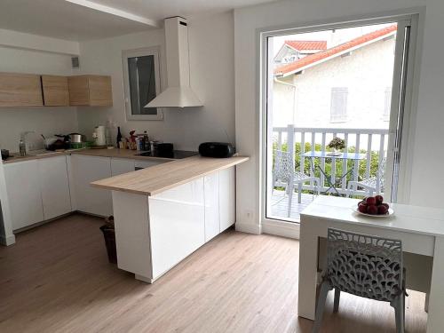 une cuisine avec des placards blancs et une grande fenêtre dans l'établissement Charmant T2 rénové avec balcon, parking privé, à 2 pas des plages de Capbreton pour 4 personnes - FR-1-239-1071, à Capbreton