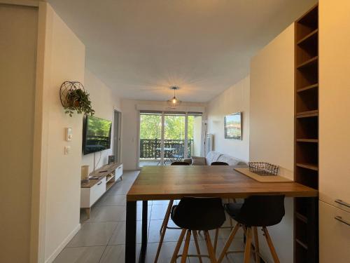 - une cuisine et un salon avec une table en bois et des tabourets dans l'établissement Charmant T2 proche plages et commerces avec terrasse à Vieux-Boucau - FR-1-239-1072, à Vieux-Boucau-les-Bains