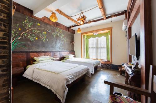 a bedroom with two beds and a painting on the wall at Butterfly Flowers Inn in Zhangjiajie