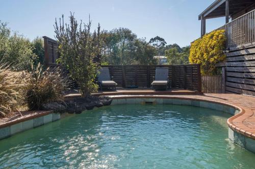 a pool in a backyard with chairs in the water at Port Philip Panorama - Bayview Retreat and Pool Bliss in Mount Martha