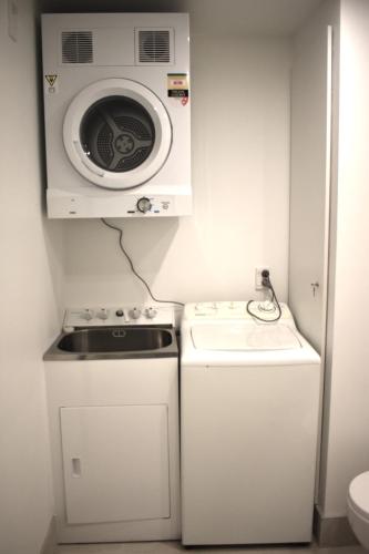 a small kitchen with a microwave and a washer and dryer at 6 on Adams in Mount Maunganui