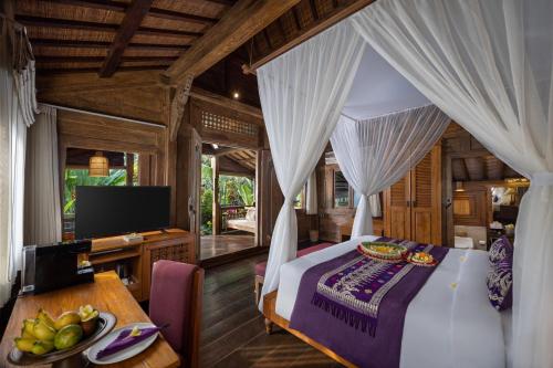 a bedroom with a bed and a desk and a television at Pramana Watu Kurung in Ubud