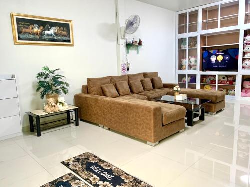 a living room with a brown couch and two tables at BAAN OZONE HY2 in Hat Yai