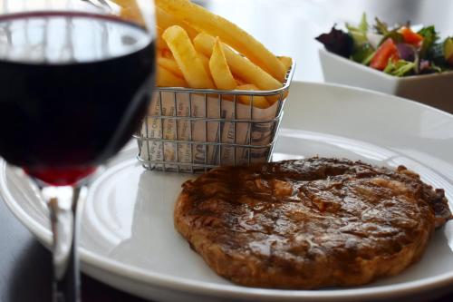 a plate with a steak and french fries and a glass of wine at Holiday Inn Parramatta by IHG in Sydney