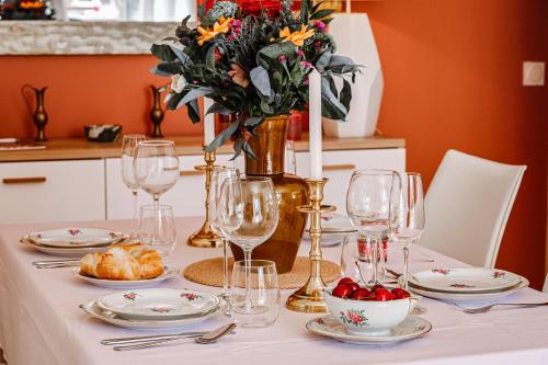 une table avec des assiettes et des verres et un vase avec des fleurs dans l'établissement La Bohème - VILLA PAULA, à Istres