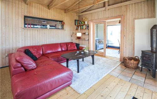 a living room with a red leather couch and a table at Holiday Home Kobbelsti I in Klitmøller