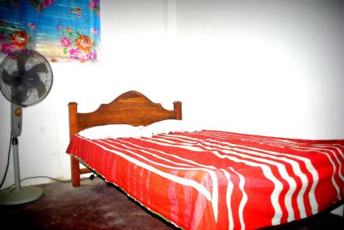 a bedroom with a red and white bed with a fan at Meemure Rawana Adawiya in Meemure