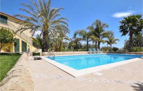 a swimming pool with chairs and palm trees at 5 Bedroom Awesome Home In Noto in Noto