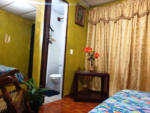 Un dormitorio con un inodoro y un jarrón de flores sobre una mesa. en SHALOM HOME, en Santa Ana