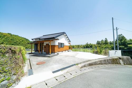 a small house with a driveway next to a road at 妹川ロッジ in Kugumiya