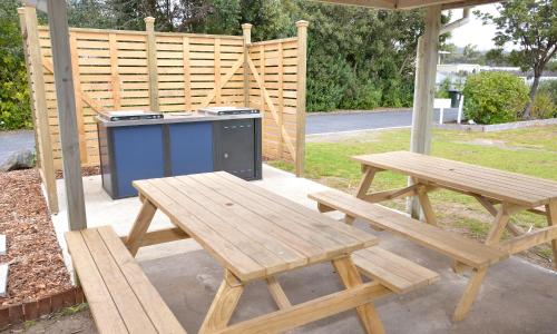 a picnic table and a bench and a stove at Camp Waipu Cove in Waipu
