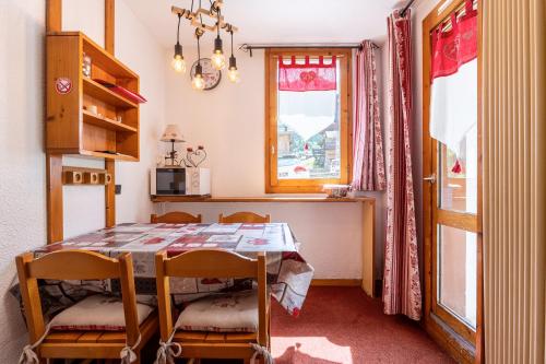 une cuisine avec une table et des chaises et une fenêtre dans l'établissement La Bûche, à Valmorel