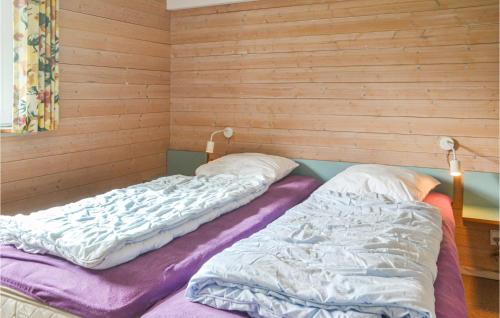 two beds in a room with wooden walls at Holiday Home Nørre Nebel 37 in Lønne Hede
