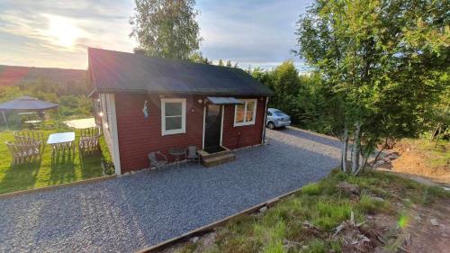 a small red cabin with a car parked in front at Fully renovated cottage with great hilltop views in Undenäs