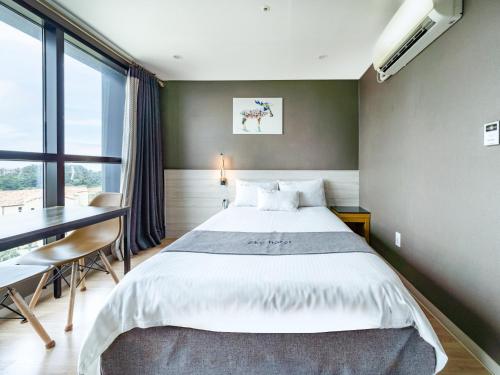 a bedroom with a large bed and a desk and a window at Sky Hotel in Jeju