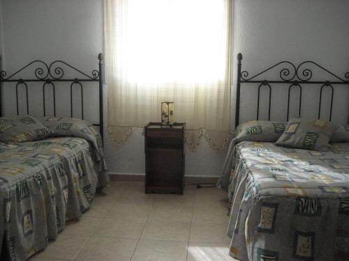 Un dormitorio con dos camas individuales y una ventana. en Residencial Augusta, en Islantilla