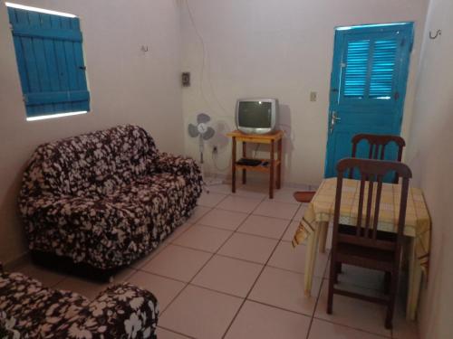 a living room with a couch and a table and a tv at Casa Mobiliada Galinhos in Galinhos