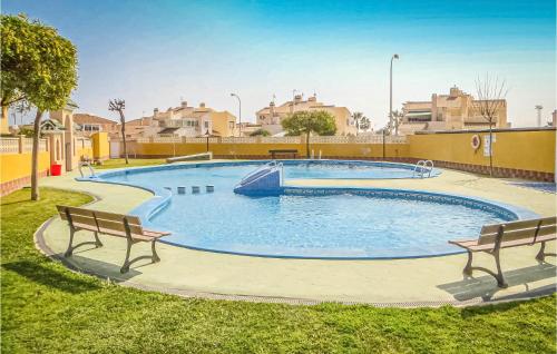 a large swimming pool with two benches around it at Urb Al Andalus I in Villamartin