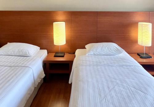two beds in a hotel room with two lamps at BU Place Hotel in Bangkok