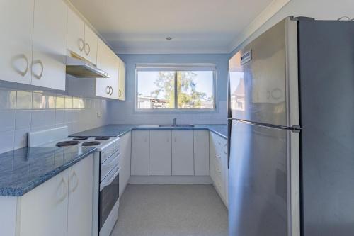 a kitchen with white cabinets and a stainless steel refrigerator at Perfect for Two Families in Sussex inlet