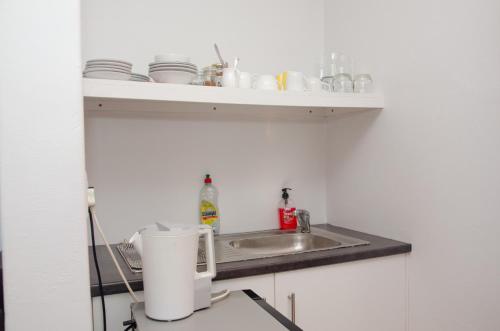 a kitchen counter with a sink and a shelf with dishes at Fijnbos Manor in Bettyʼs Bay
