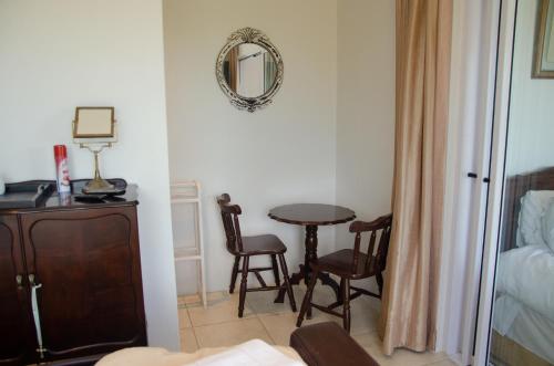 a room with a table and two chairs and a mirror at Fijnbos Manor in Bettyʼs Bay