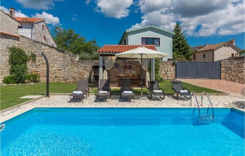 a pool with chairs and an umbrella next to a house at Holiday Home Barban V in Barban