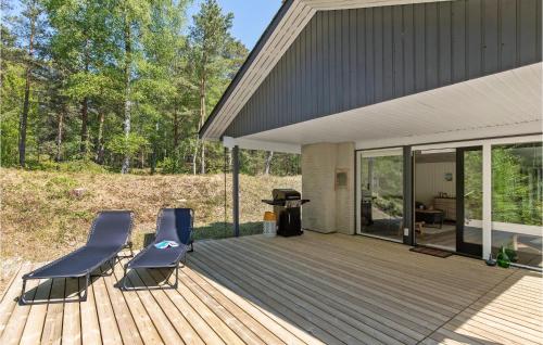 una terraza de madera con 2 sillas y una parrilla en Holiday Home Nexo L, en Spidsegård