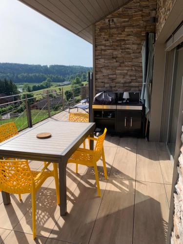un patio avec une table, des chaises et un barbecue dans l'établissement Vue lac, à Montperreux