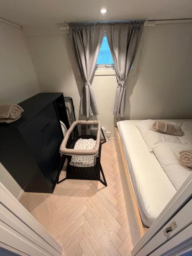 une petite chambre avec un lit et une chaise dans l'établissement Entire renovated apartment from 1780 with Kitchen, Bath, Bedroom, and Living Room in Skuteviken, à Bergen