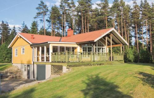 a large yellow house with a large deck at Stunning Home In Lidhult With Lake View in Lidhult