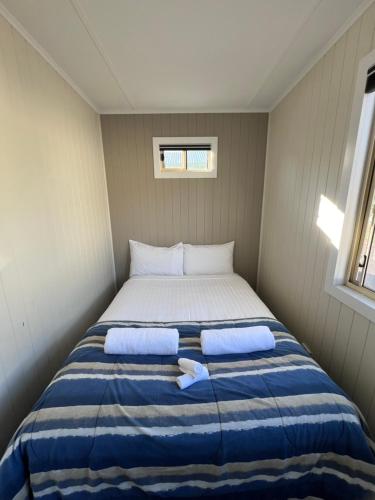 a bed in a small room with two pillows at Strahan Beach Tourist Park in Strahan