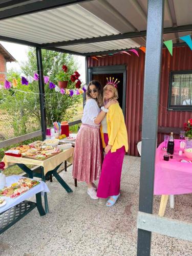 two women standing next to each other in front of a table at Šuma za odmor in Mladenovac
