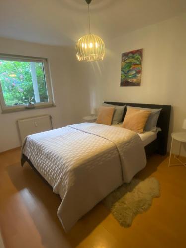 a bedroom with a bed and a window and a chandelier at In Saarbrücken Stadtnahe gemütliche Wohnung am Deutsch-Französischen Garten in Saarbrücken